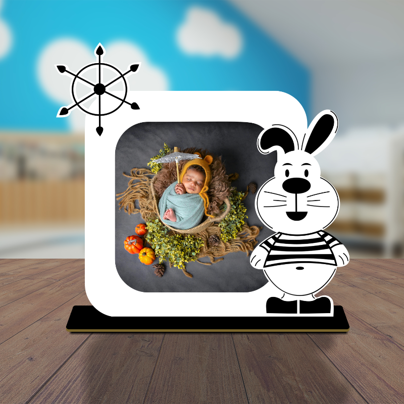 A colorful wooden bunny-shaped photo frame with a personalized photo of a baby inside. The frame has a black base with a white bunny motif, and a blue easel back.