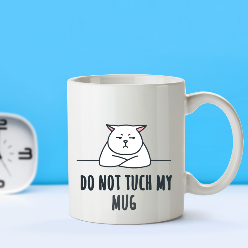 A white ceramic coffee mug with a printed black and gray design of a cat and the text 'DO NOT TOUCH MY MUG'.