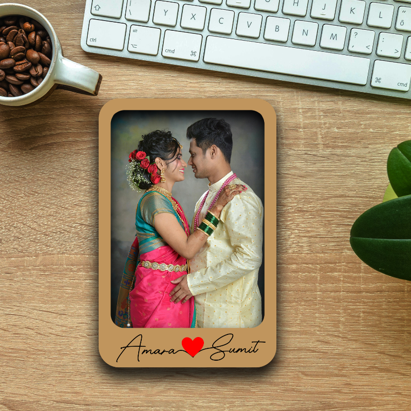 Wooden photo frame with a couple in traditional attire on a wooden desk with a keyboard and coffee cup.