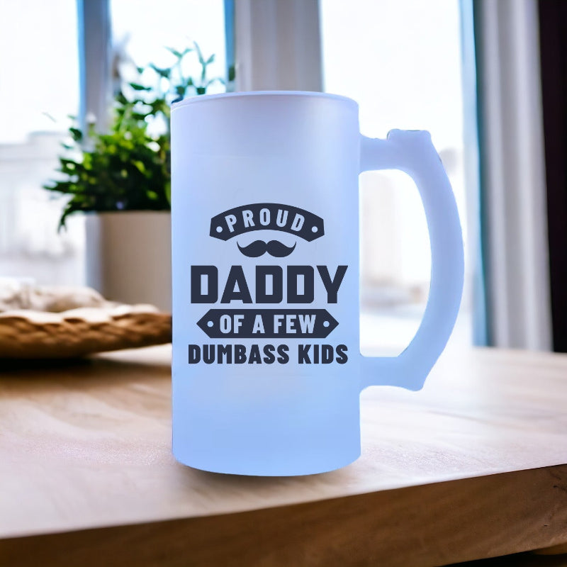 Frosted mug with text 'Proud Daddy of a Few Dumbass Kids' on a wooden surface.