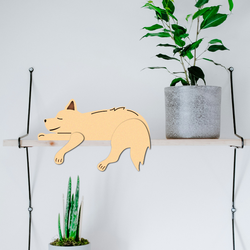Wooden fox decoration on a shelf with a plant against a white background