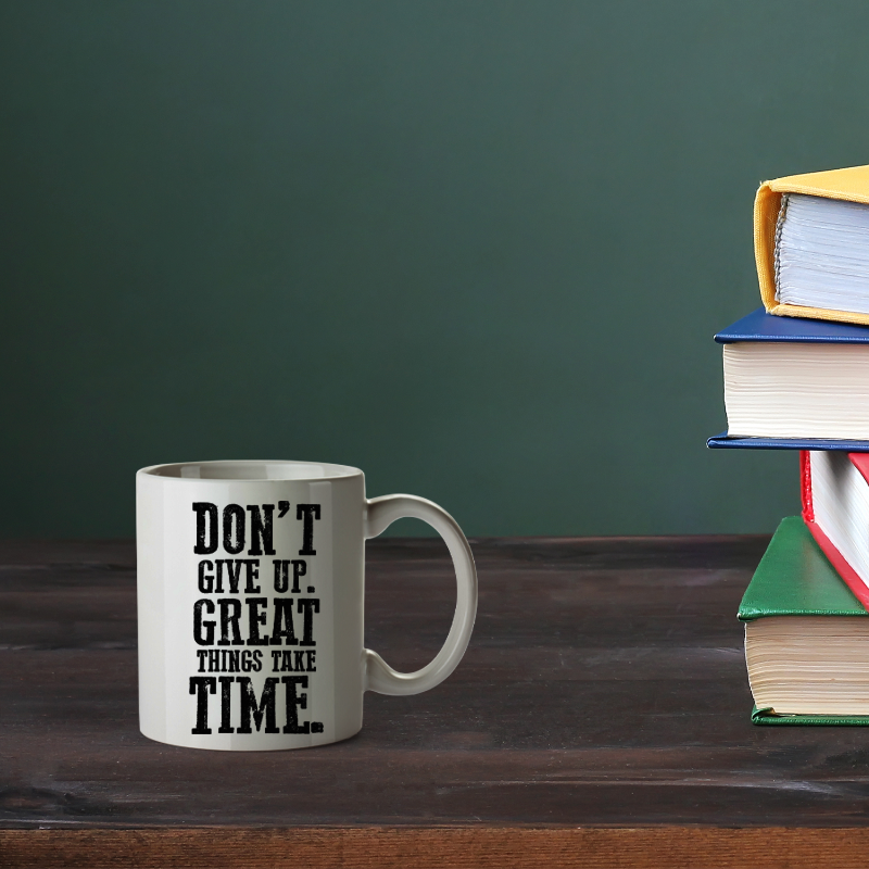 Mug with motivational quote on a wooden surface with books in the background