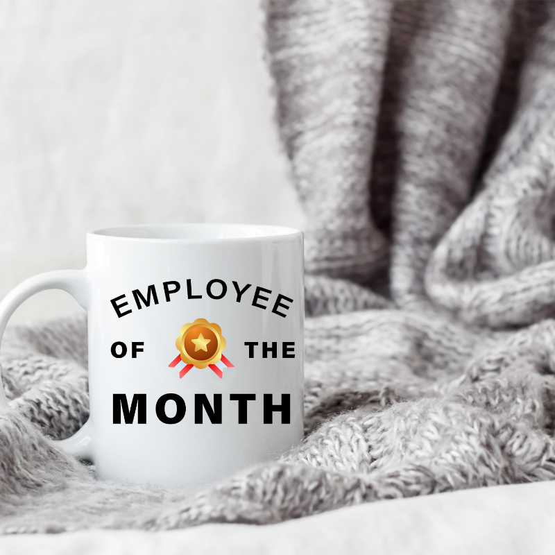 White mug with 'Employee of the Month' text on a textured surface