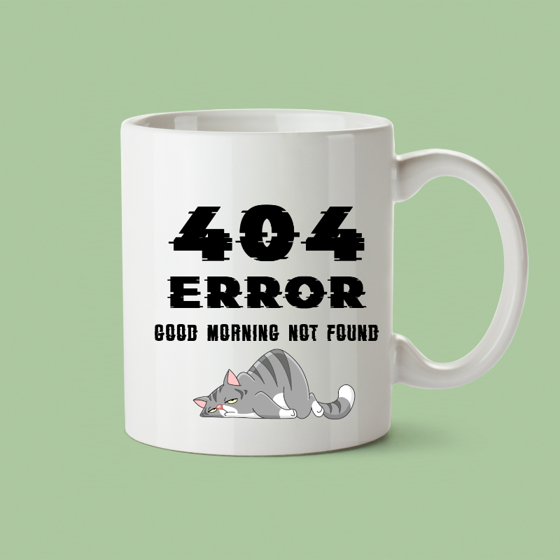 A white ceramic coffee mug with text '404 ERROR GOOD MORNING NOT FOUND' printed on it, accompanied by an illustration of a sleeping cat.
