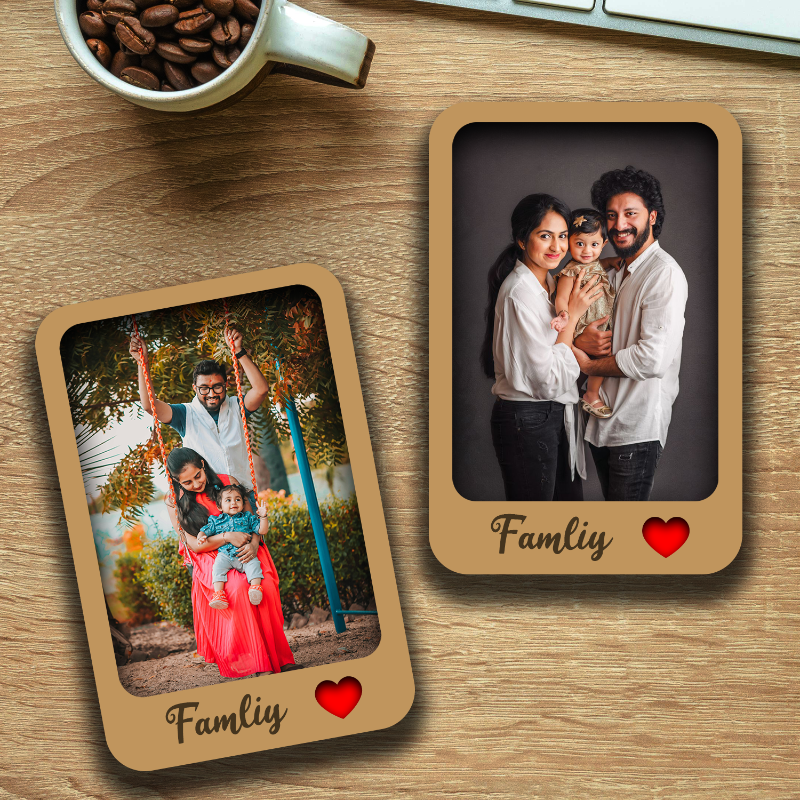 Two personalized family photo fridge magnets on a wooden surface. One magnet has a photo of a family with children, and the other has a photo of a couple.