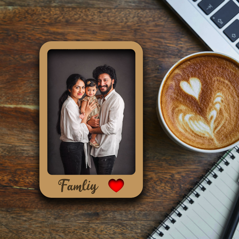 Family photo in a wooden frame on a wooden table with a cup of coffee and laptop.