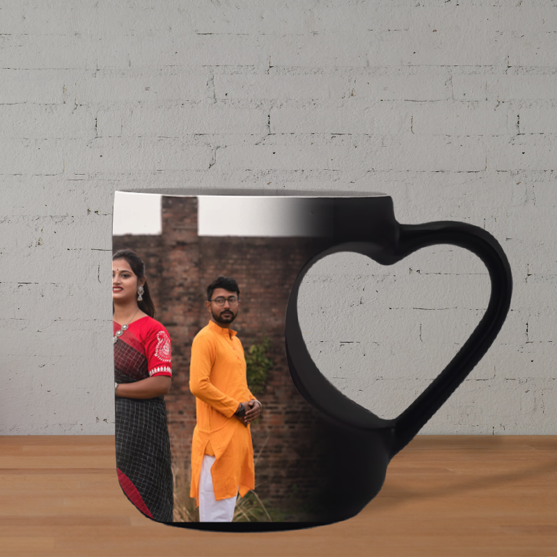 Black mug with a heart-shaped handle featuring a printed design of a couple against a brick wall.
