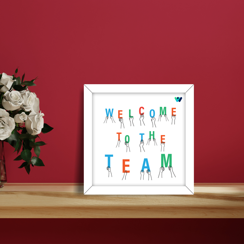 Framed artwork with 'Welcome to the Team' text on a red wall with flowers.