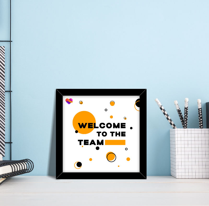 Framed poster with 'Welcome to the Team' text on a light blue wall.