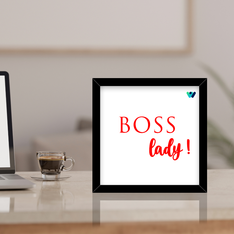 Framed sign with 'BOSS lady!' text on a desk with a laptop and coffee.