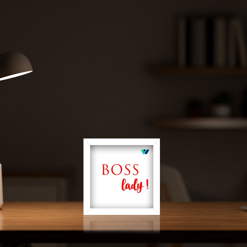 Framed sign with 'BOSS lady!' text on a desk with a blurred background