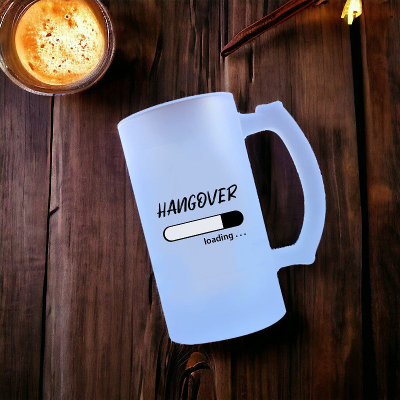 Frosted mug with 'Hangover loading...' text on a wooden surface with a lit candle.