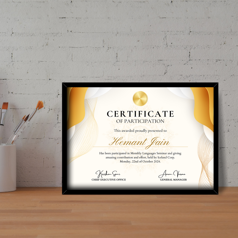 A framed participation award certificate displayed on a table with artistic paintbrushes and a brick wall in the background.