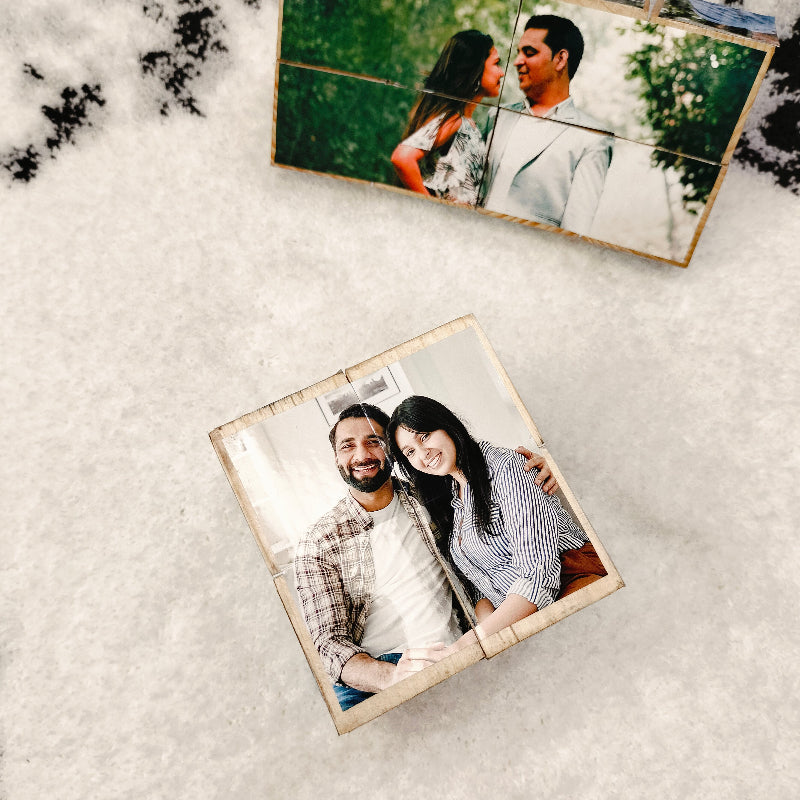 A wooden rolling cube with personalized photos printed on each face, displaying images of a couple in love.