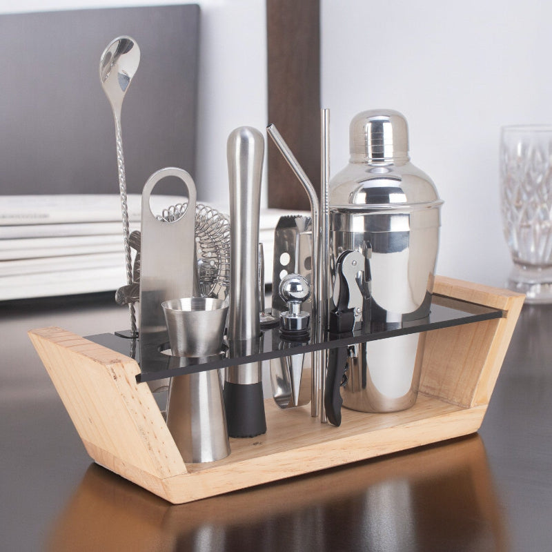 Set of cocktail-making tools including a shaker, jigger, and strainer on a wooden stand.