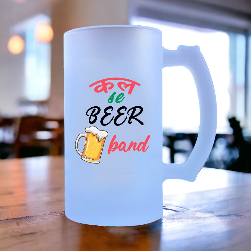 Frosted mug with colorful text and beer illustration on a wooden table.