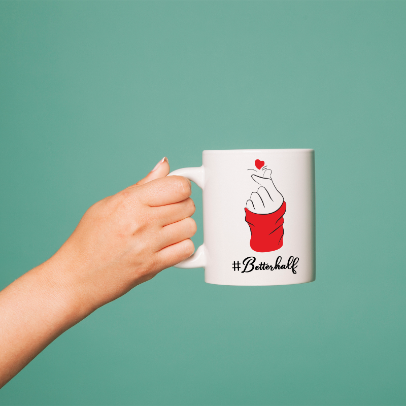 Hand holding a mug with a '#Bettehralf' design on a teal background