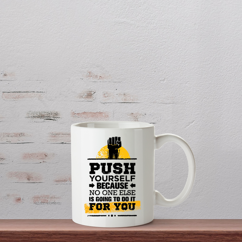 White mug with motivational quote on a wooden shelf against a light gray wall.