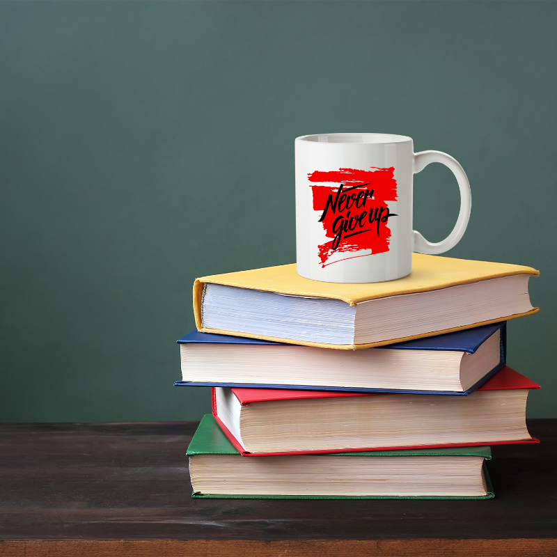 Stack of books with a mug labeled 'Never Give Up' on a green background