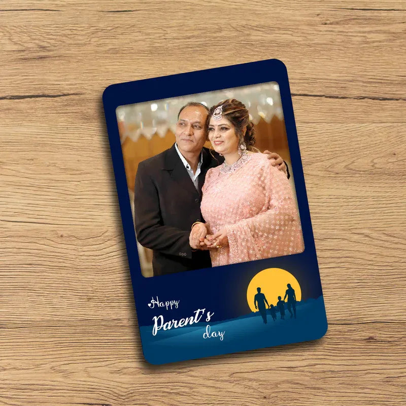 Parent fridge magnet with a couple on it and 'Happy Parents Day' text on a wooden surface.