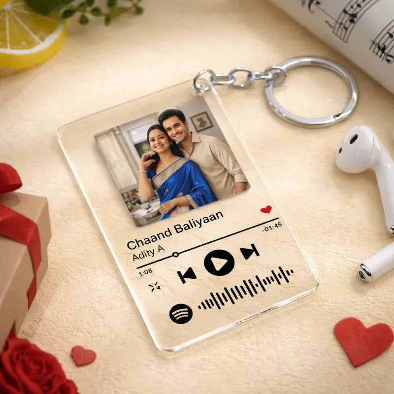Personalized keychain with music player design and photo of a couple on a light wooden surface.