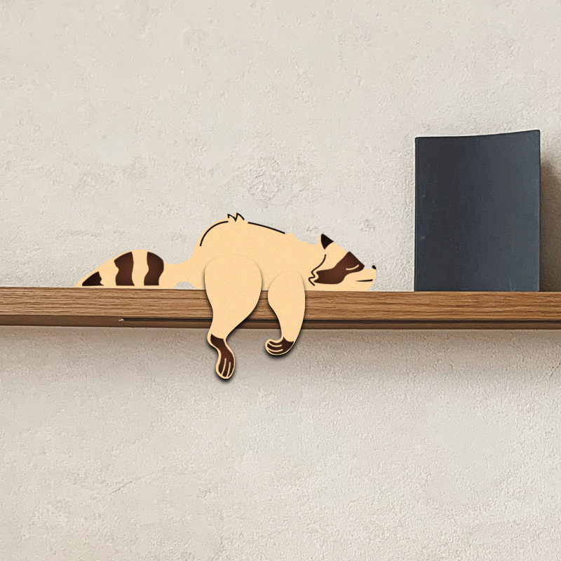 Wooden raccoon-shaped decorative item on a shelf against a neutral wall.
