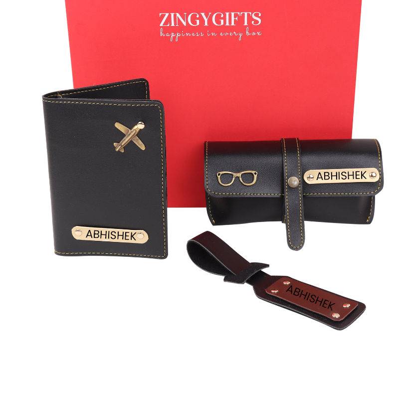 A set of black personalized travel accessories including a passport holder, sunglass cover, and a bag tag with the name 'Abhisek' inscribed on each piece, presented on a red background.