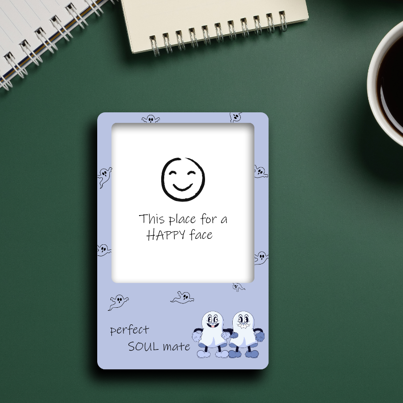 Small rectangular frame with a smiley face design on a green surface with a notebook and coffee cup.
