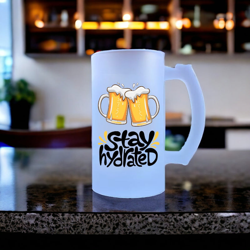 Frosted mug with beer design and 'Stay Hydrated' text on a bar counter.