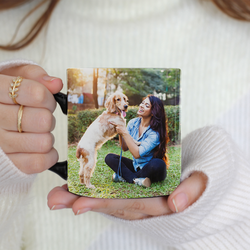 A person holding a ceramic mug with an image of themselves and their pet dog on it.