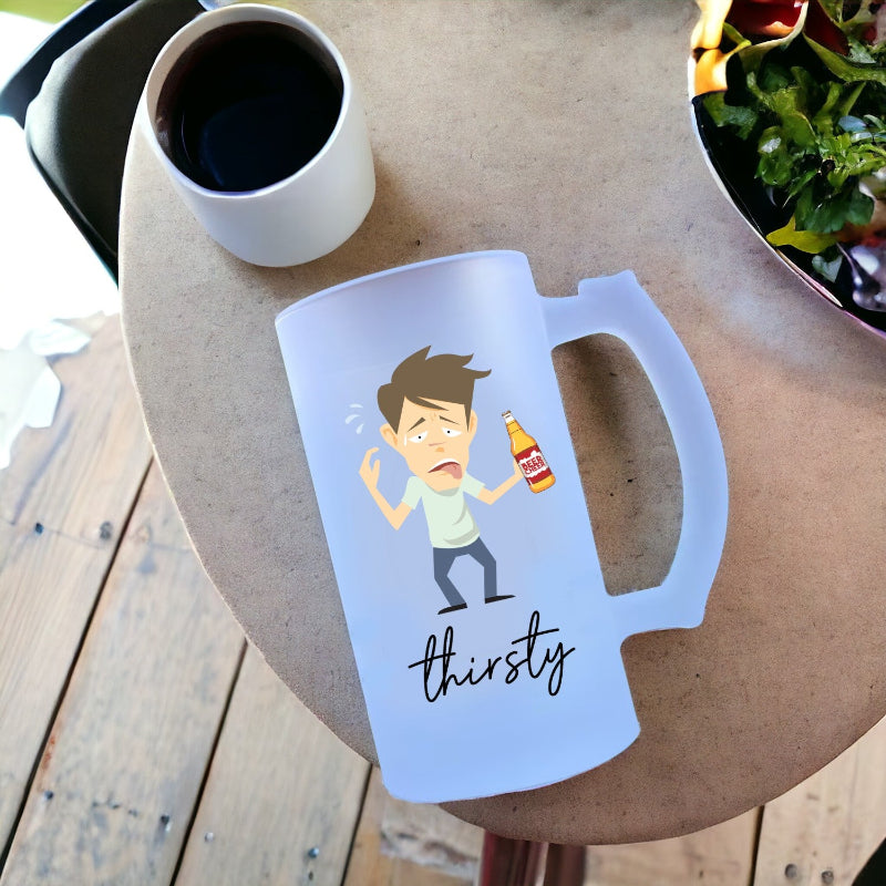 Transparent mug with cartoon character and 'thirsty' text on a wooden table with a cup and salad.