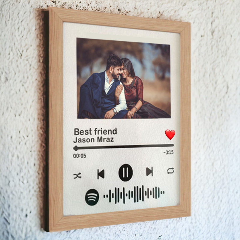Framed artwork with a photo of a couple and music player interface on a textured wall.
