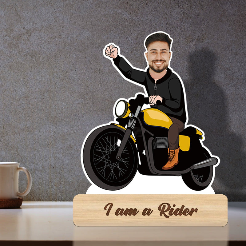 A 3D caricature of a man on a yellow motorcycle, with a wooden stand included, placed on a table.