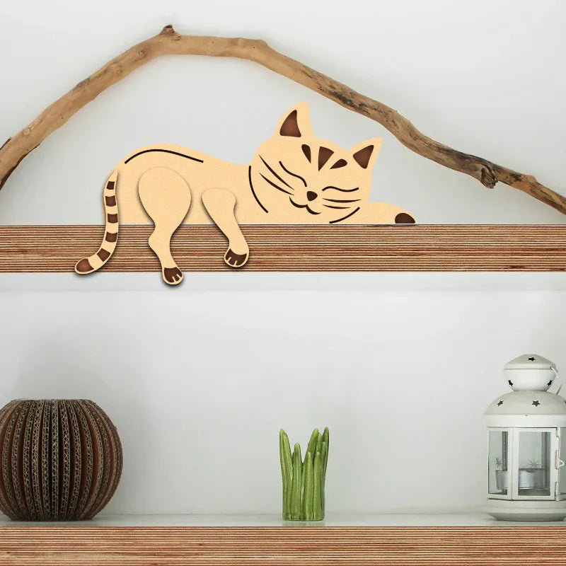 Wooden cat decoration on a branch with a white wall and decorative items below.