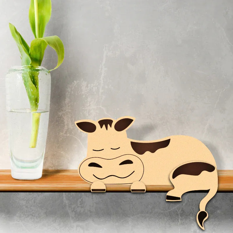 Wooden cow decoration on a shelf with a plant in the background