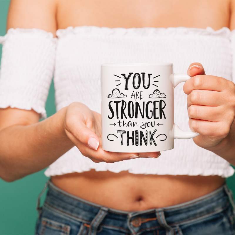 Person holding a mug with 'You are stronger than you think' text against a teal background