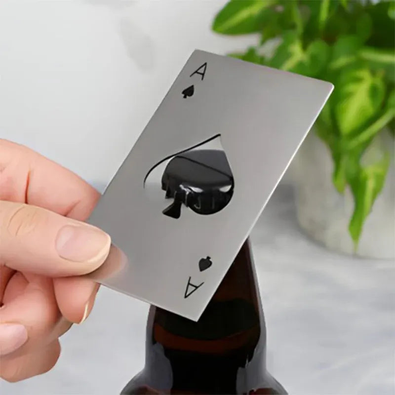 Hand holding a bottle opener metallic playing card with an ace of spades design against a neutral background.