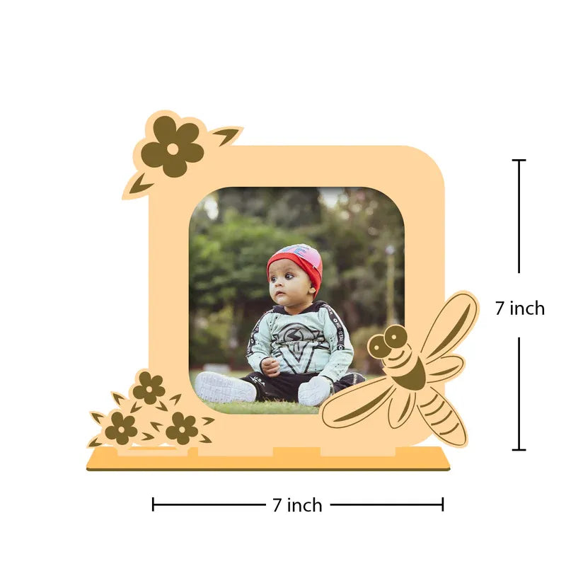 Wooden photo frame with floral and dragonfly designs, showing a child's photo inside, on a white background.