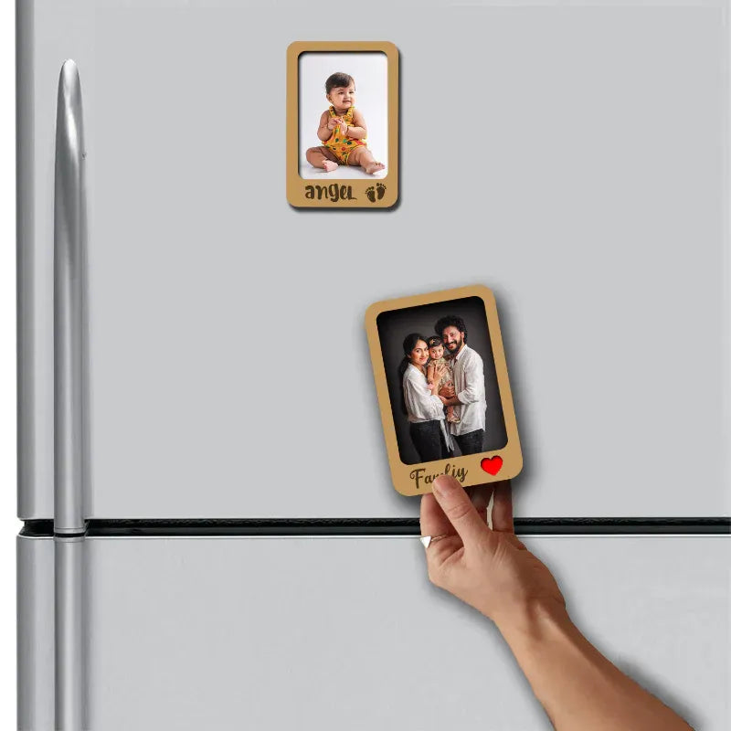 Hand placing a wooden photo frame magnet on a refrigerator with another magnet showing a family photo.