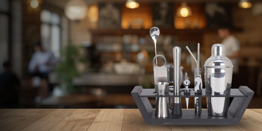 Set of bar cocktail-making tools on a tray with a blurred bar background
