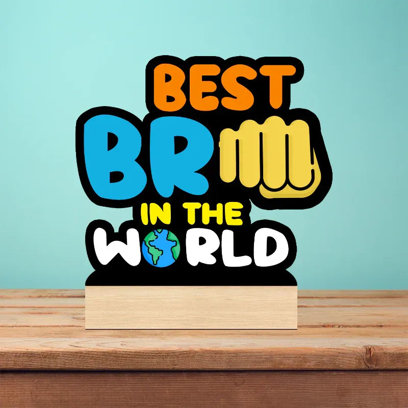 A 3D acrylic LED light sign on a wooden block base displaying the text 'BEST BRILLIANT IN THE WORLD' with a globe icon, set against a light blue background and wooden table.