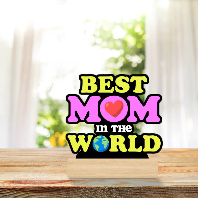 Decorative sign with 'Best Mom in the World' text on a wooden surface.