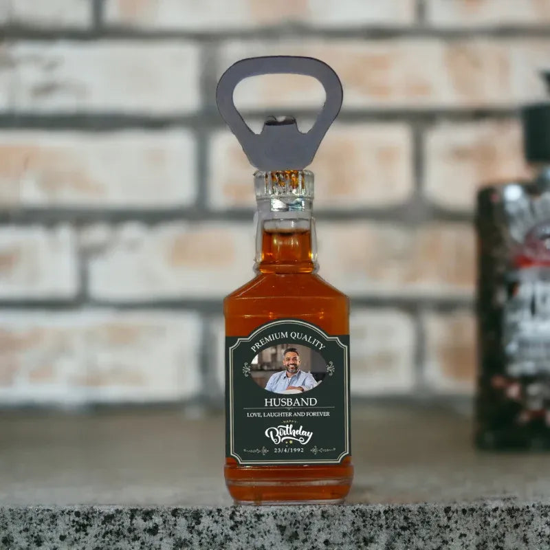 Bottle opener fridge magnet with a miniature bottle labeled 'Husband' on a countertop.