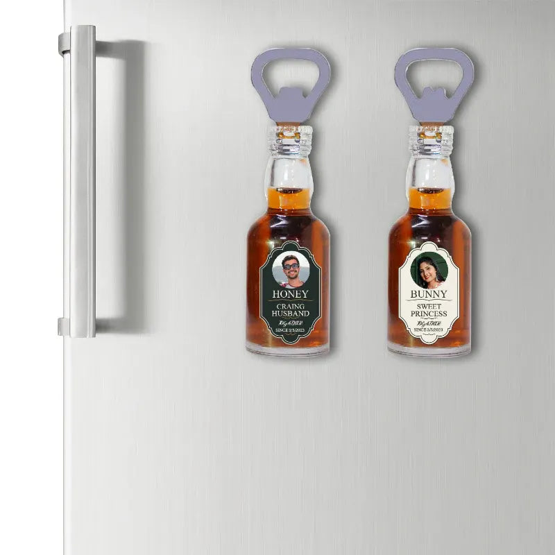 Two small bottles with labels and bottle openers attached to a refrigerator.