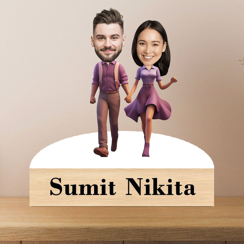 Bobblehead figures of a man and woman holding hands with a wooden base displaying 'Sumit Nikita'.