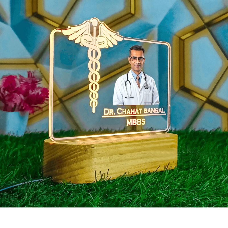 Decorative plaque with a doctor's photo and name on a grassy surface with flowers in the background
