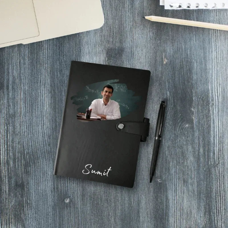 Black notebook with a photo of a man and the name 'Sumit' on a wooden surface.
