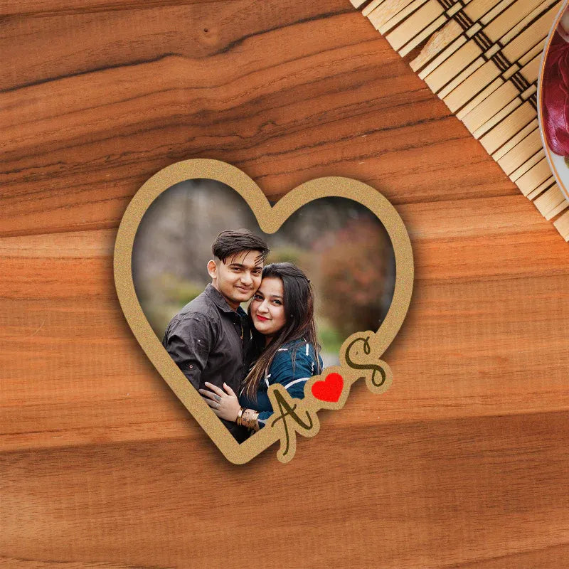 Heart-shaped photo fridge magnet with a couple's picture on a wooden surface