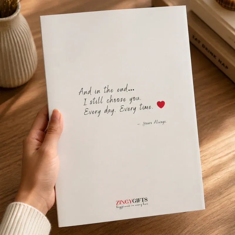 Hand holding a card with a romantic quote and heart symbol on a wooden surface.