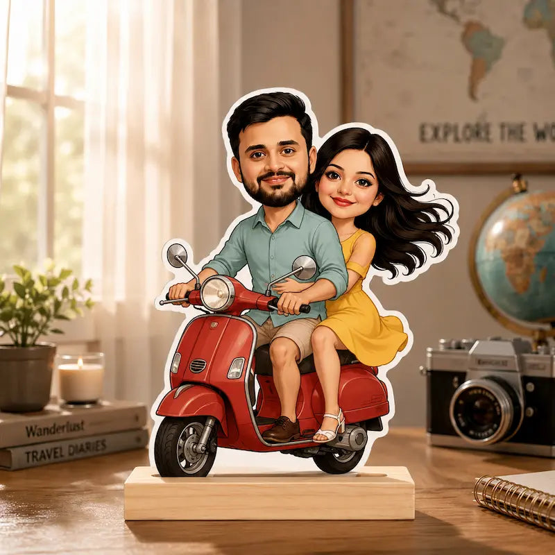 A custom cartoon couple cutout standing on a red scooter, displayed on a wooden base on a desk with a camera, globe, and books in the background.